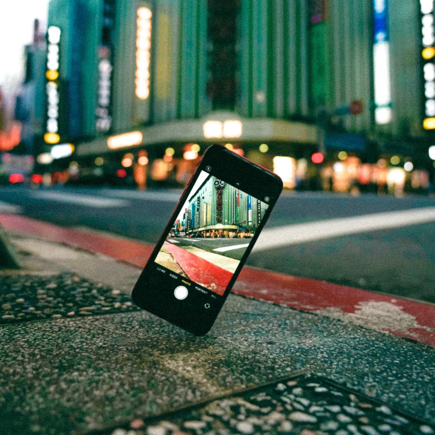 Smartphone held on a sidewalk showing a cityscape on its screen