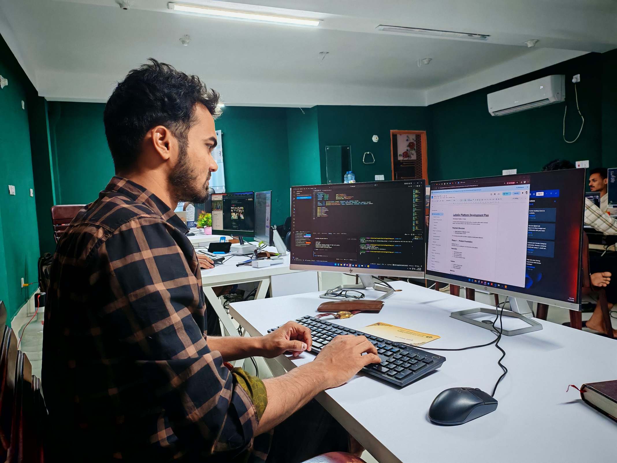 Hands typing on a keyboard with programming code on a monitor